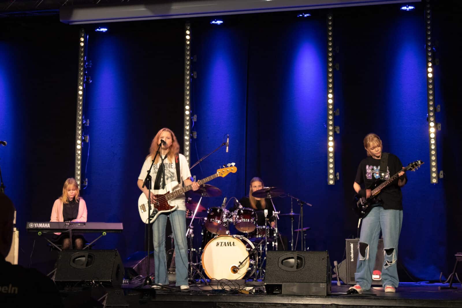 Fyra ungdomar står på en scen och spelar piano, gitarr, trummor och bas